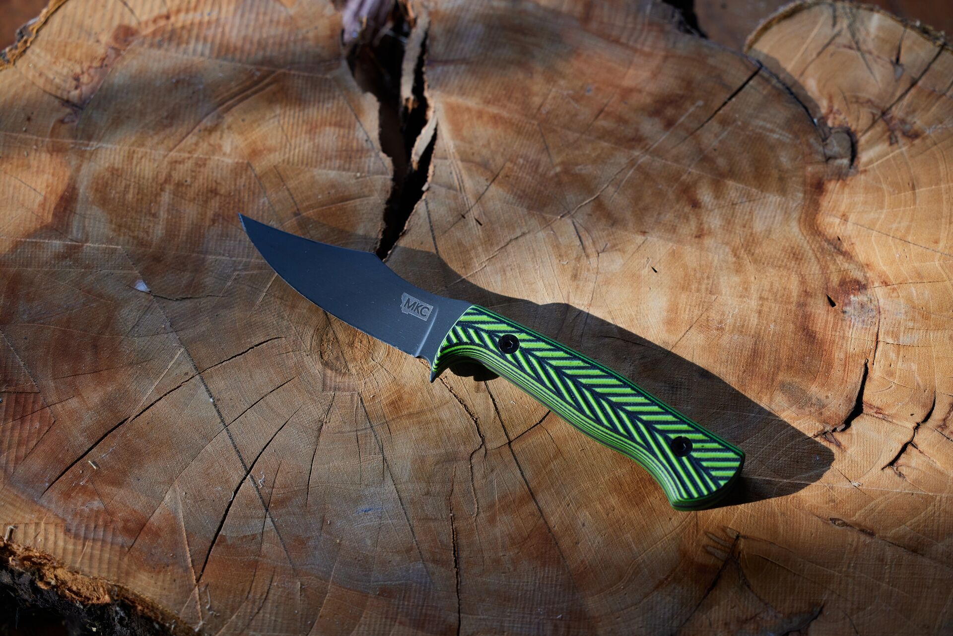 A fixed-blade knife lays on a wood stump, choosing a good hunting knife concept. 