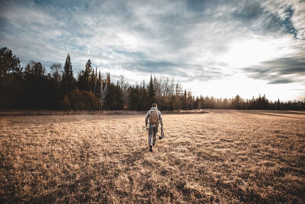 A hunter walks through a field on a cloudy day, barometric pressure and whitetail deer hunting concept. 