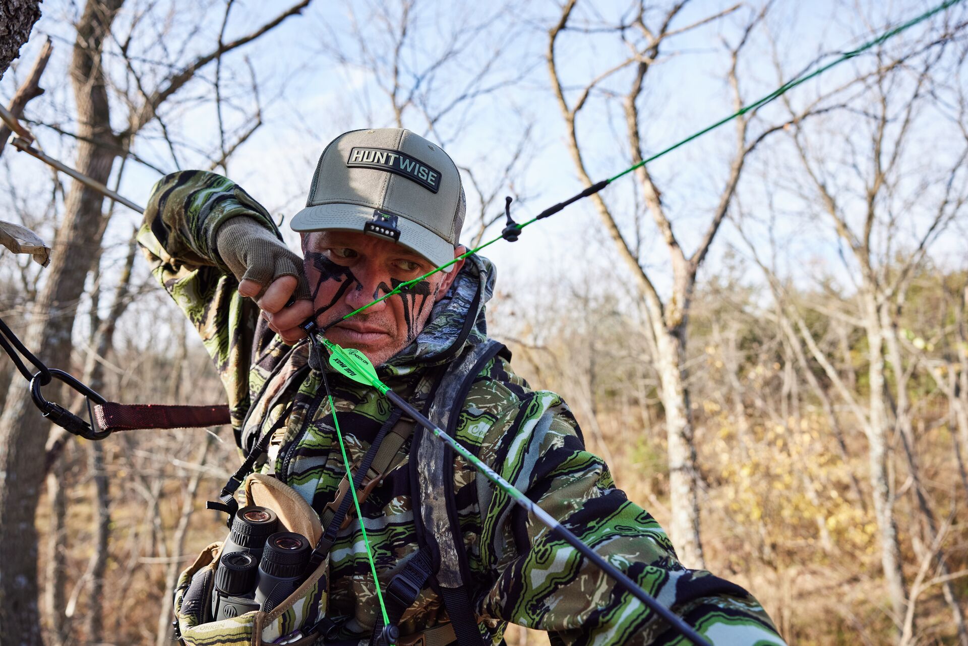 Hunter John Dudley draws a bow in the field, archery strength training concept.