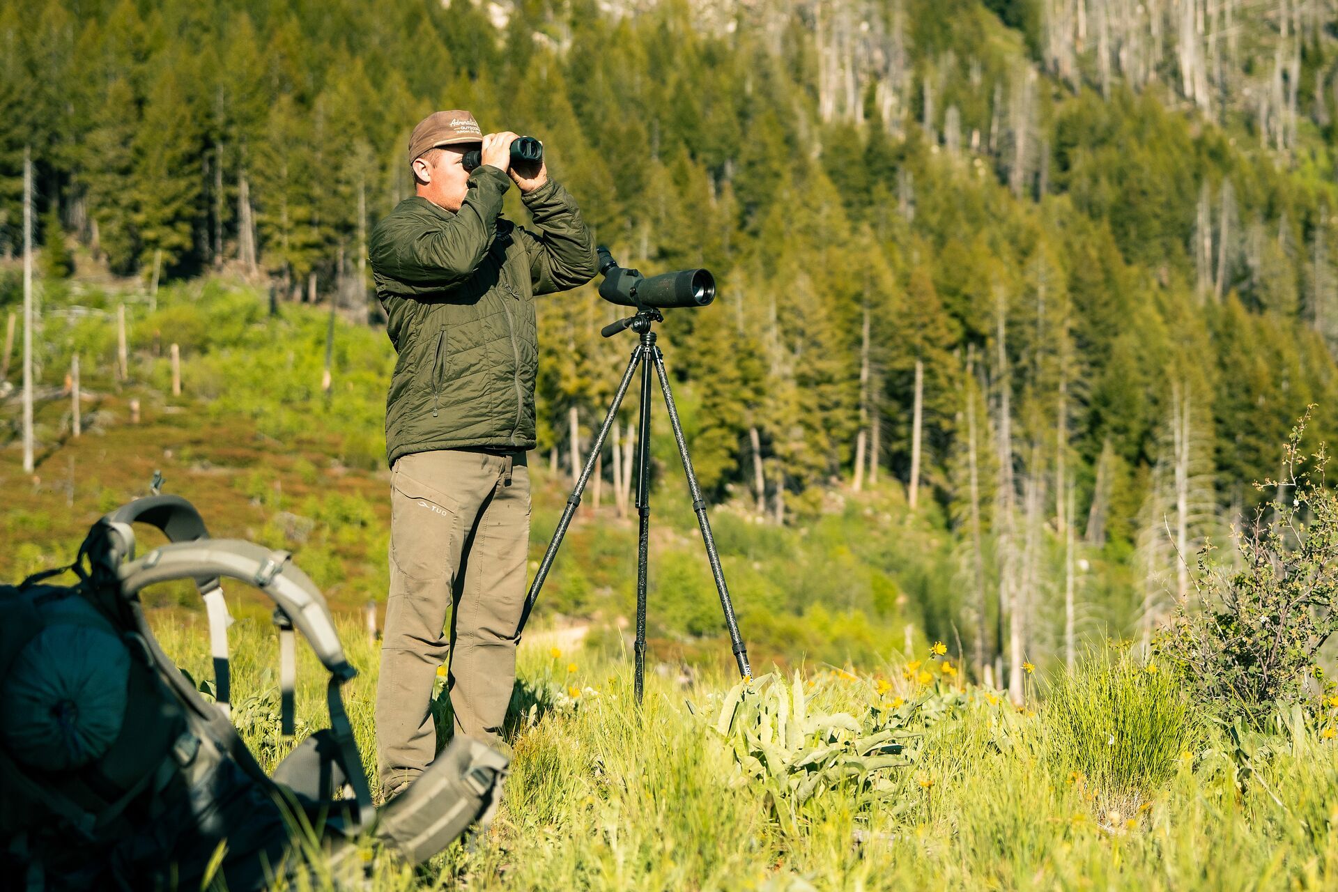 Hunter with scope looks through binoculars, plan guided elk hunt concept. 