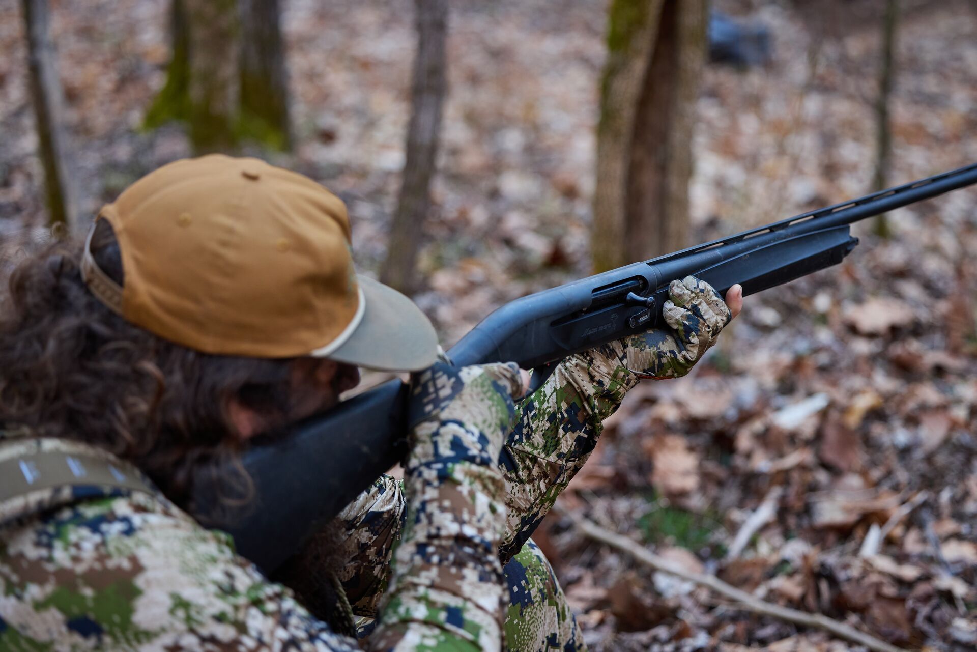 Hunter aims a shotgun during turkey hunt, 12-gauge vs 20-gauge concept. 