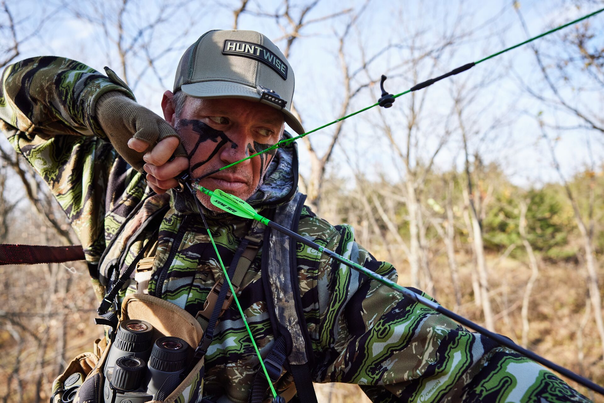 John Dudley wears a HuntWise hat and draws an arrow, how to get better at archery concept.