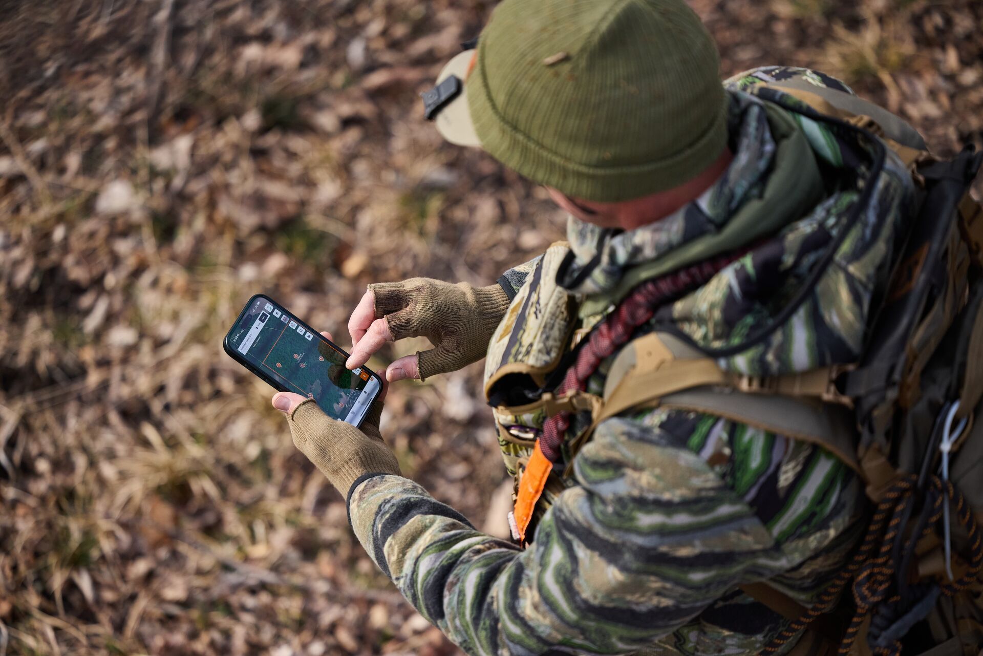 Hunter using the HuntWise app to review pins, find public deer hunting land concept. 