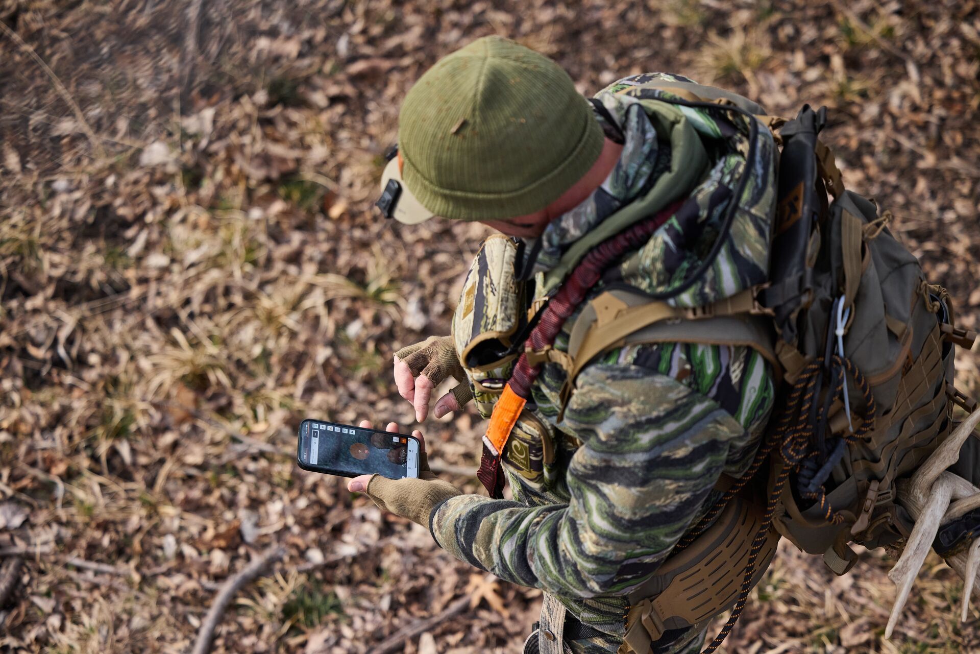 Hunter in camo using HuntWise, bow hunting elk concept.