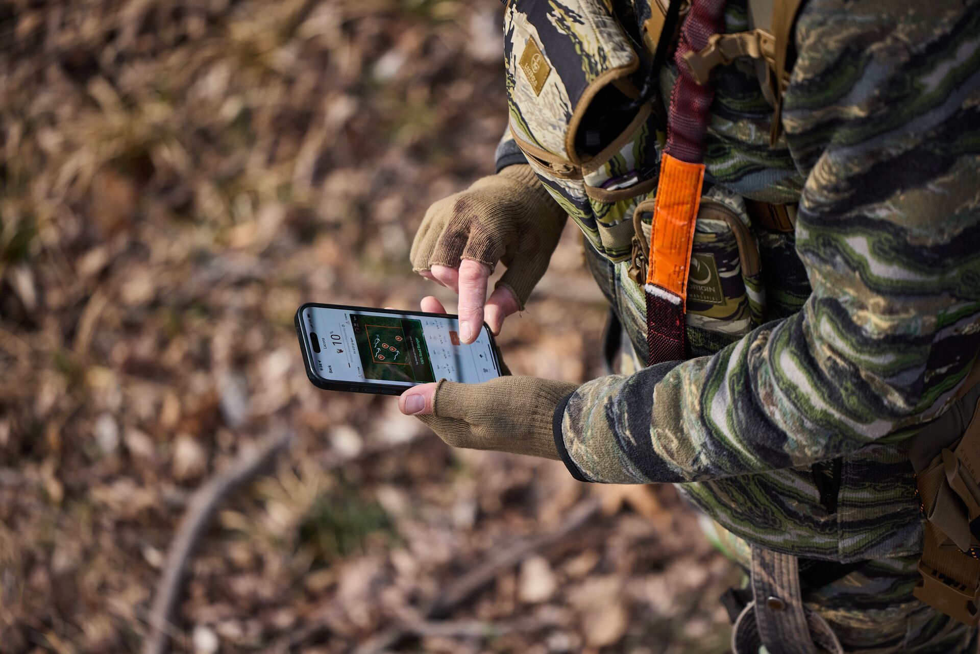 A hunter uses the HuntWise app, looking at a phone screen. 