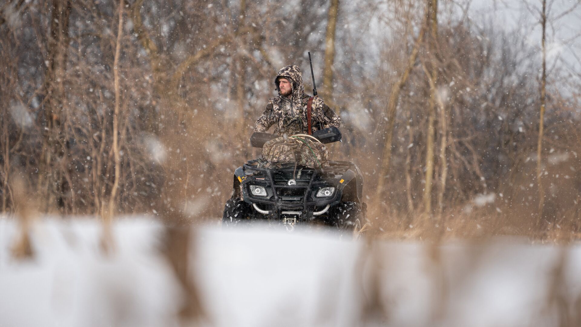 Hunter on ATV in snow, winter deer hunting strategies concept.