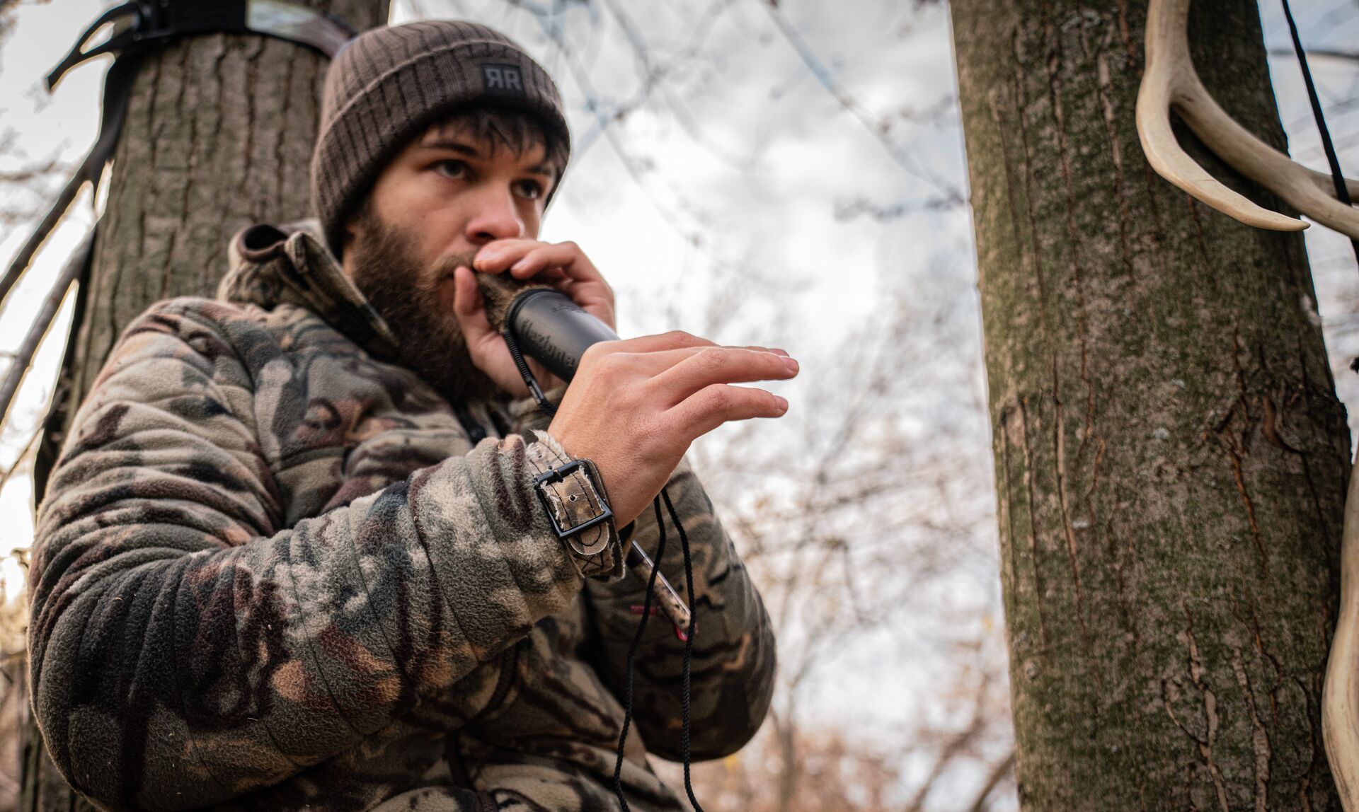 Hunter in camo using deer call, best deer grunt call tips concept. 