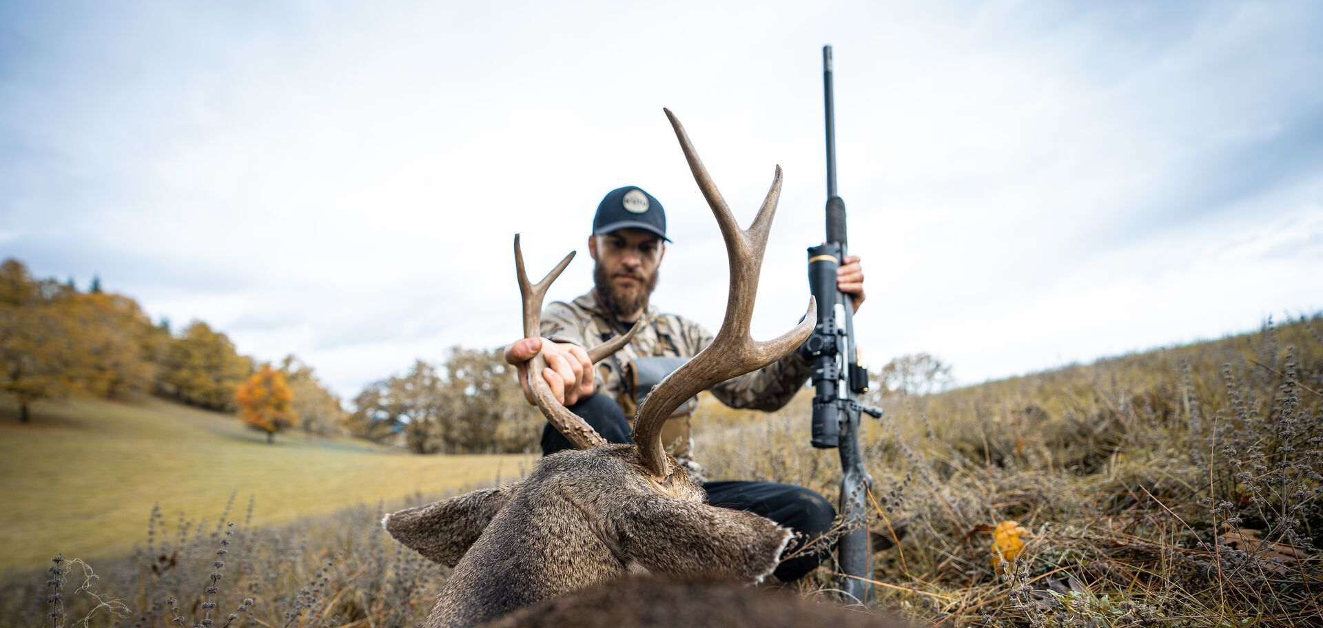 Hunter with rifle and buck deer after hunt, finding leftover hunting tags concept. 