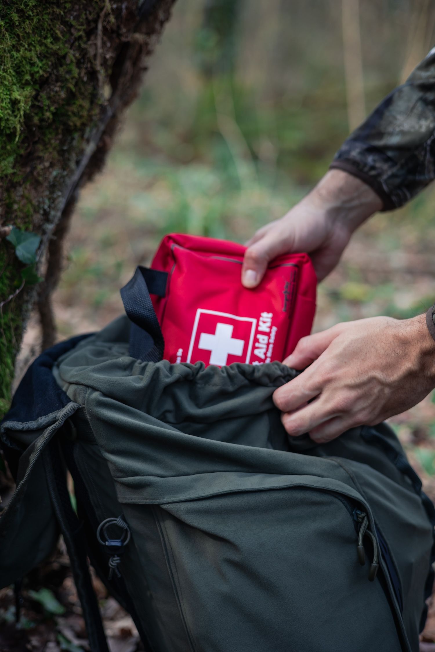 Hand putting a first aid kit into a backpack. 