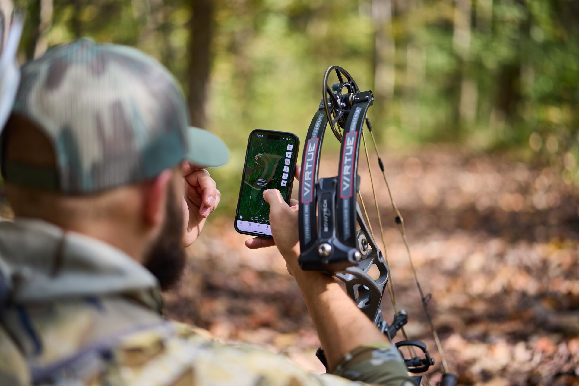 Bowhunter looks at HuntWise on phone in field, find free hunting land near me concept. 