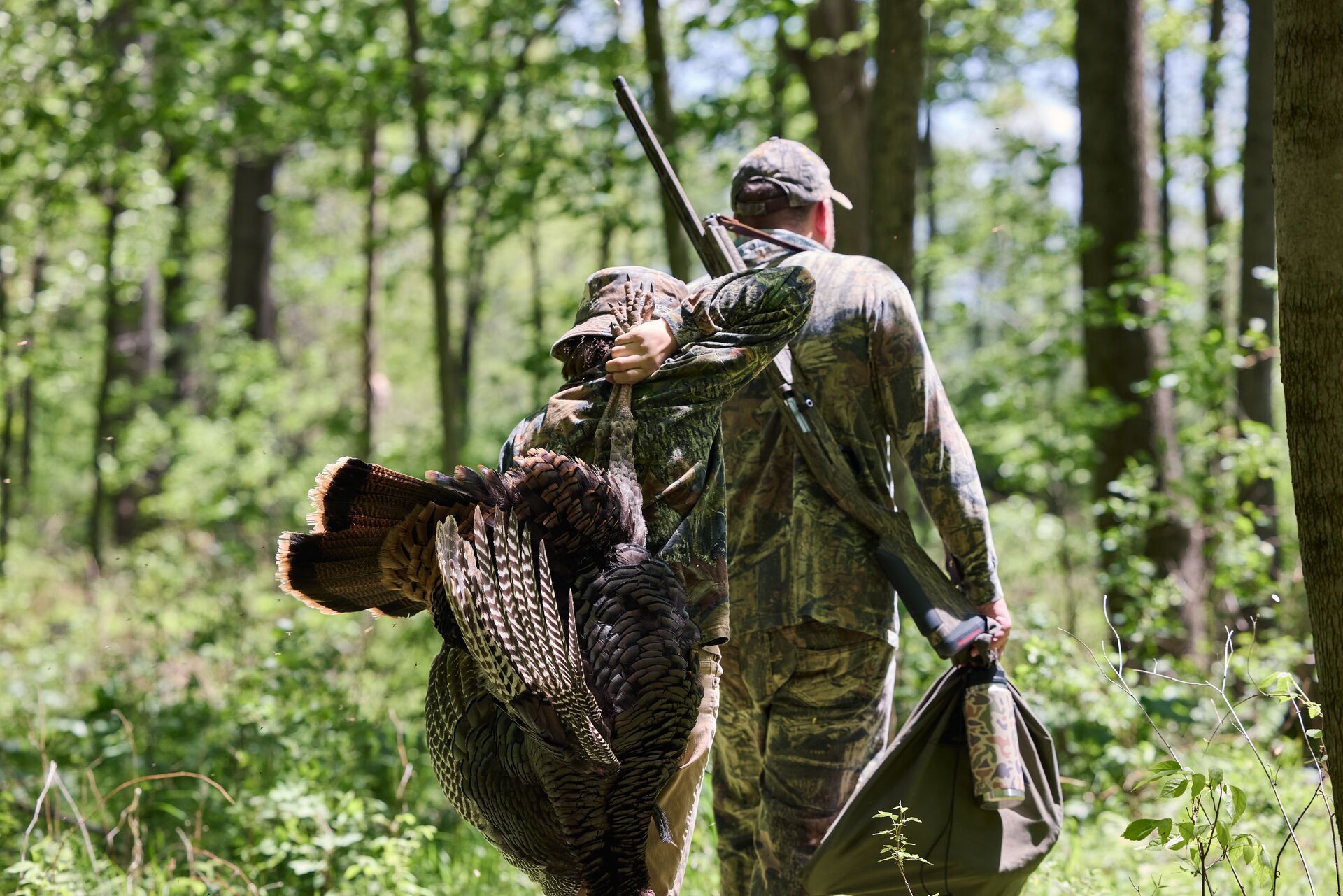 Boy carries turkey with man after hunt, turkey hunting season South Carolina concept. 