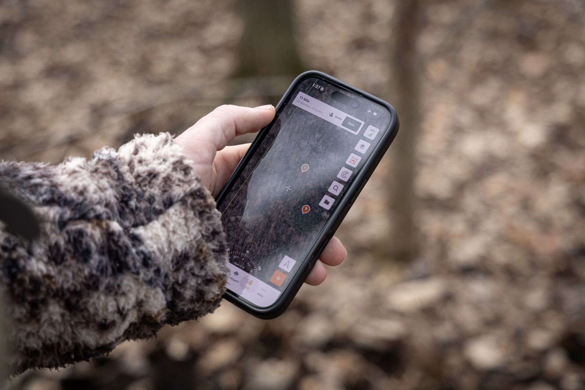 Close-up of hand holding phone showing HuntWise maps, Colorado elk hunt planning concept. 