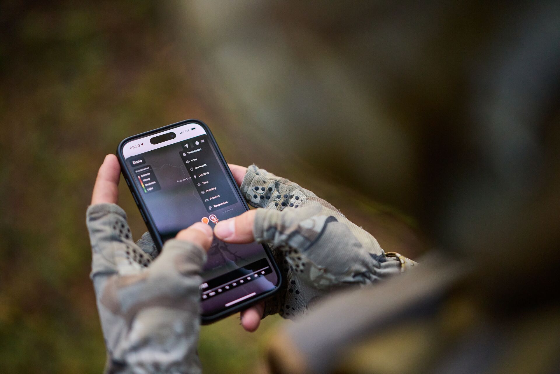 Close-up of hands holding phone using HuntWise, blacktail deer season concept. 