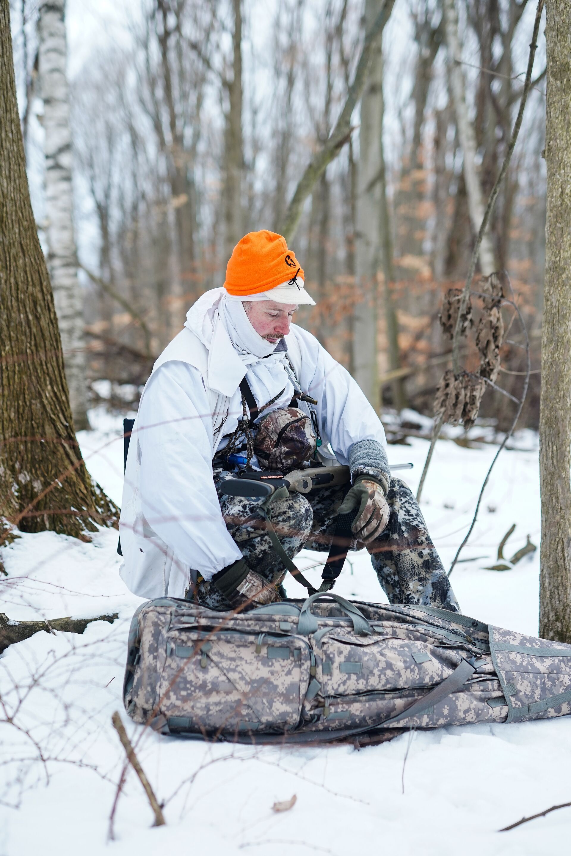 A coyote hunter gets set up in the woods, must-have coyote gear concept. 