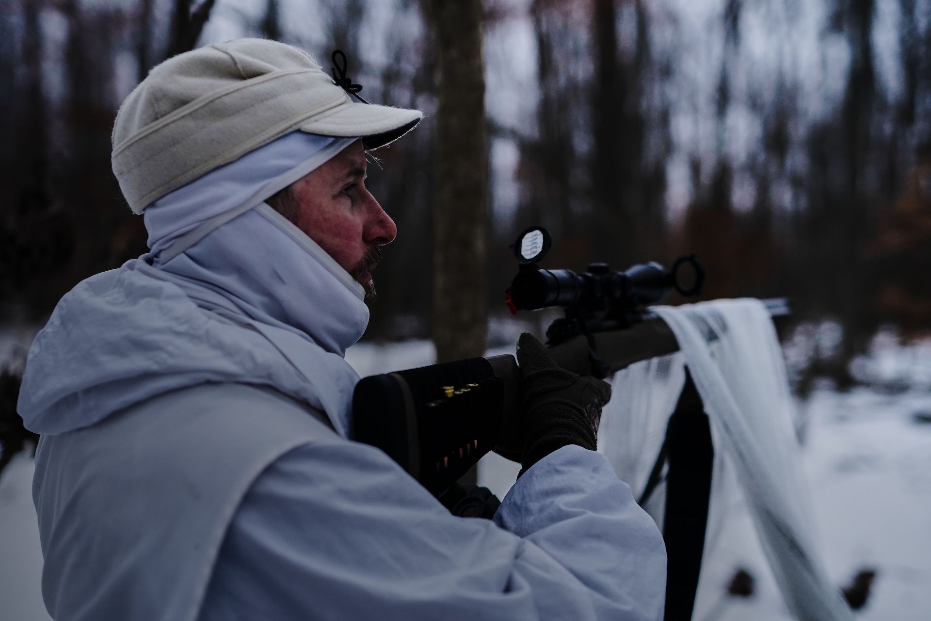 A hunter in white with a nighttime coyote hunting setup. 