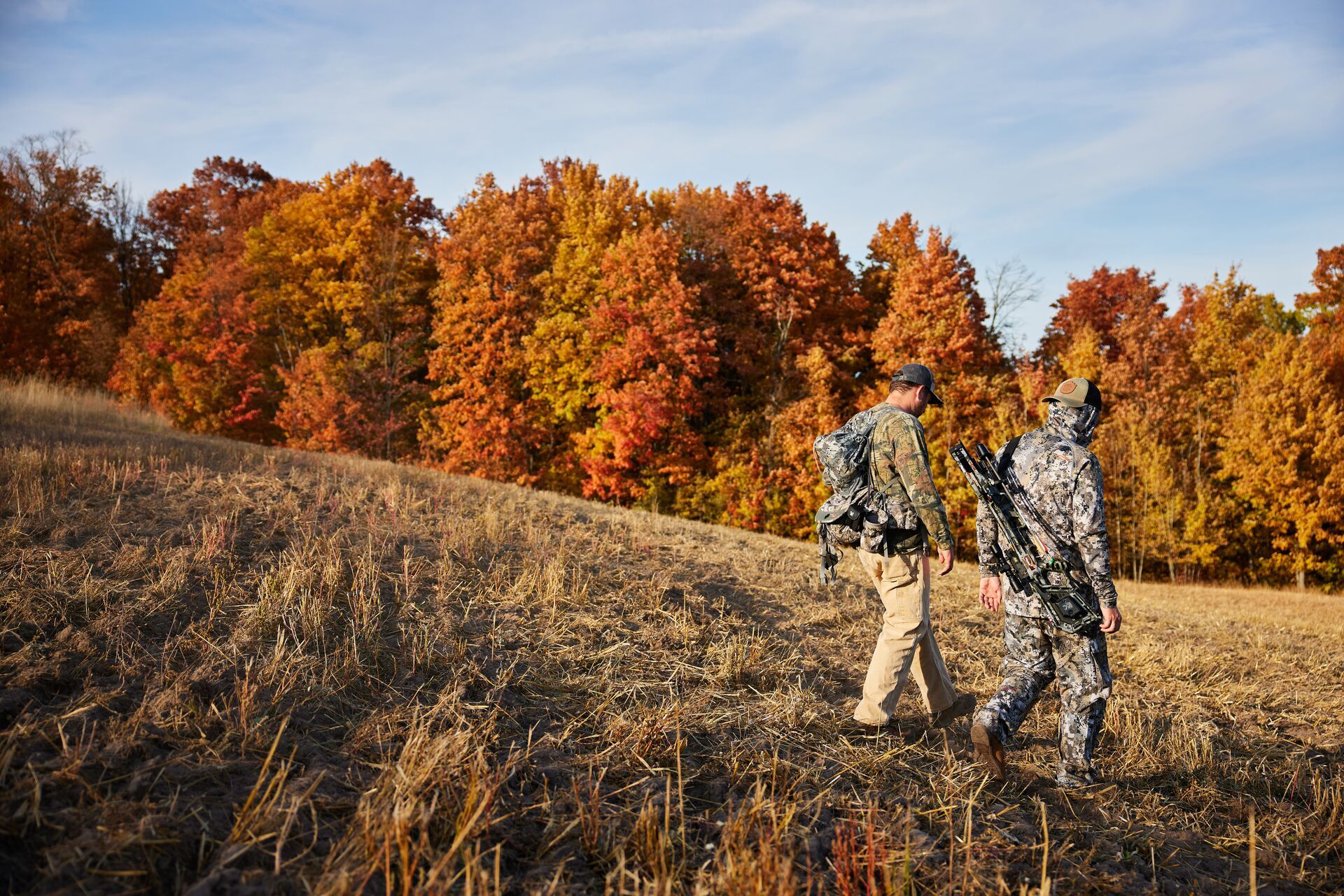 Deer hunters walking through a field in the fall. 