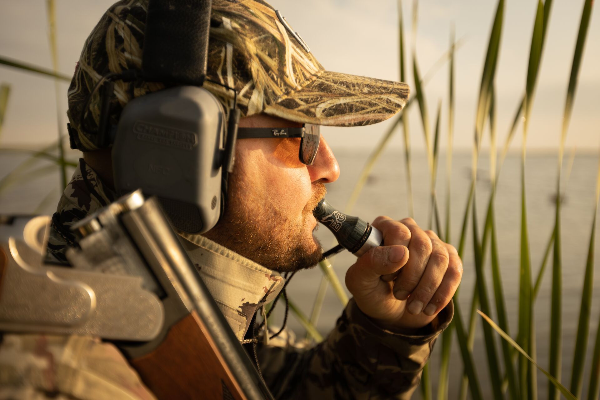 Hunter in the reeds using a duck call, how to use a duck call concept. 