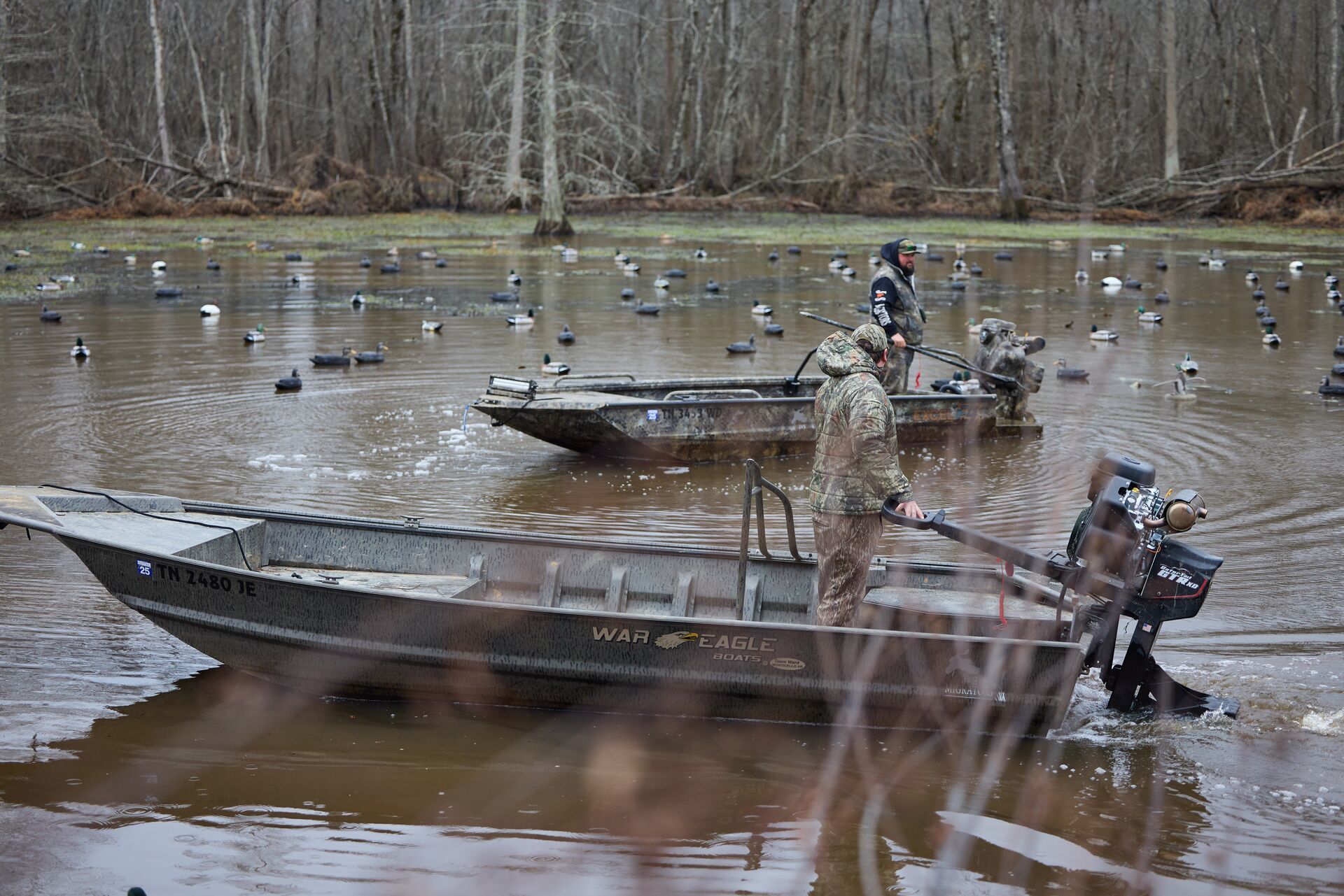 Hunters in boats setting up duck decoy spreads on water.