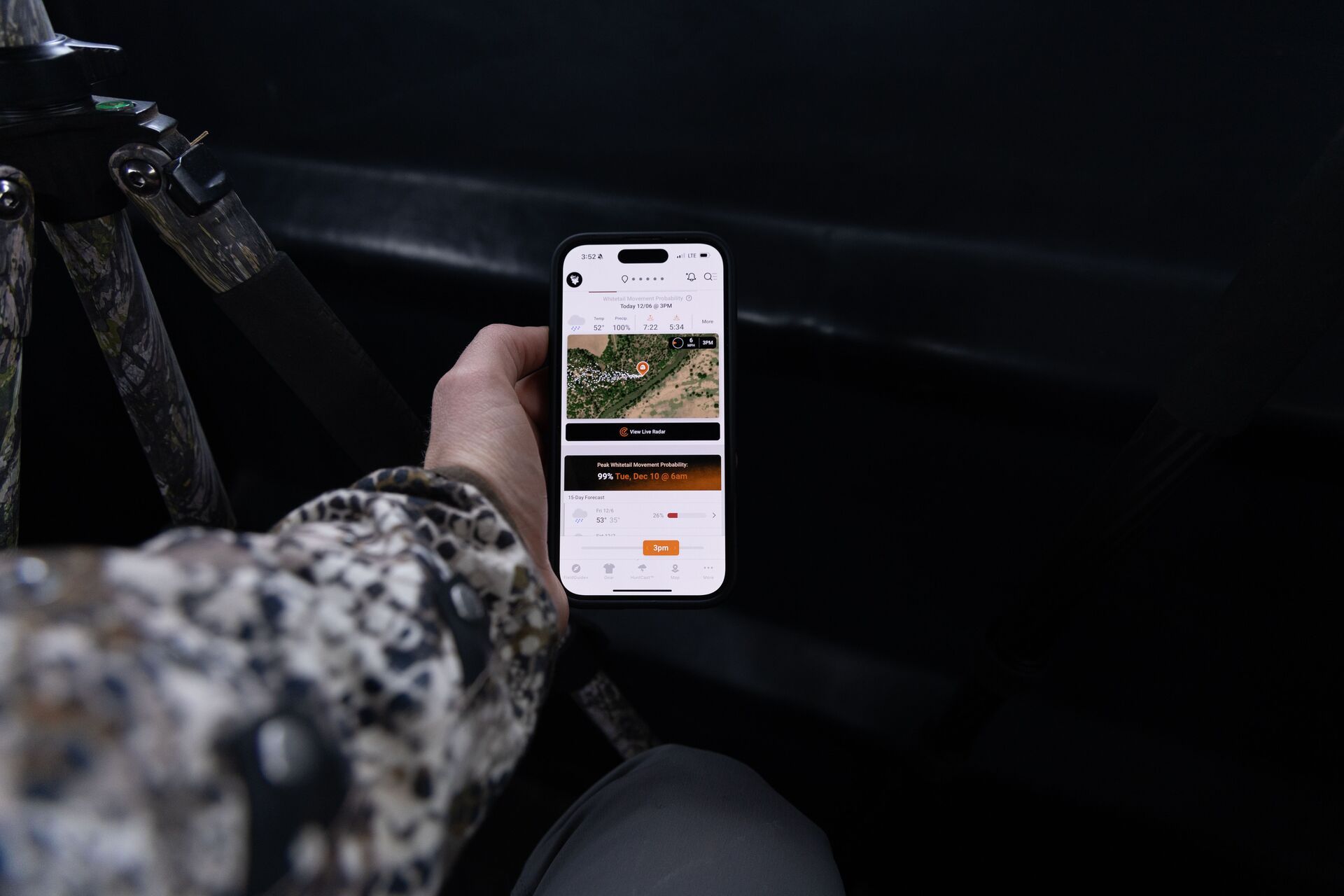 A phone shows the HuntWise hunting app in a hunter's hand. 