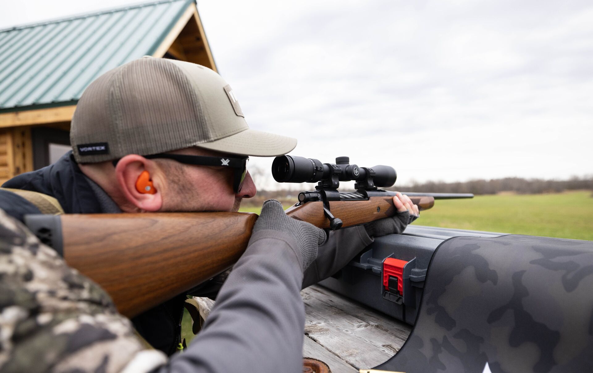 A hunter aims a rifle into the distance. 