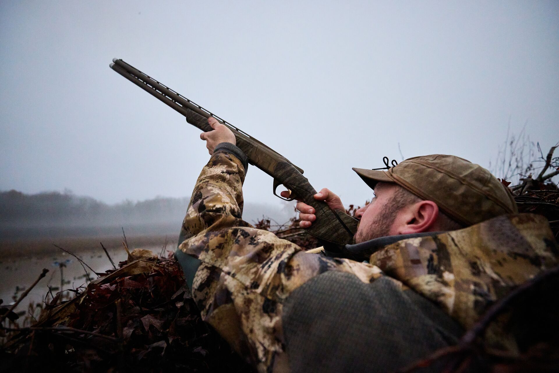 A hunter in camo aims a shotgun, best duck hunting states concept. 