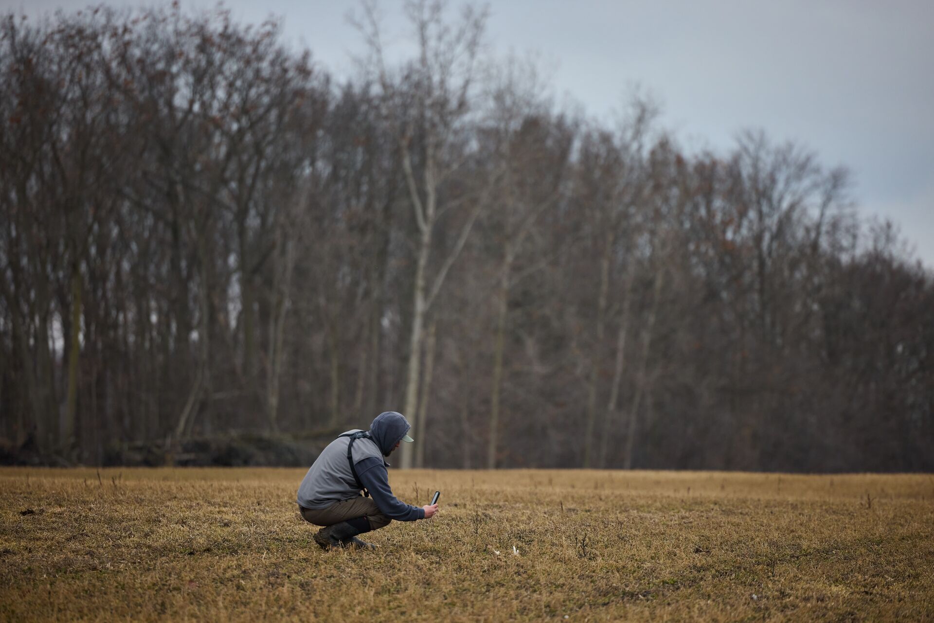 Hunter crouches to take photo of shed antler, know the best time to find sheds concept. 