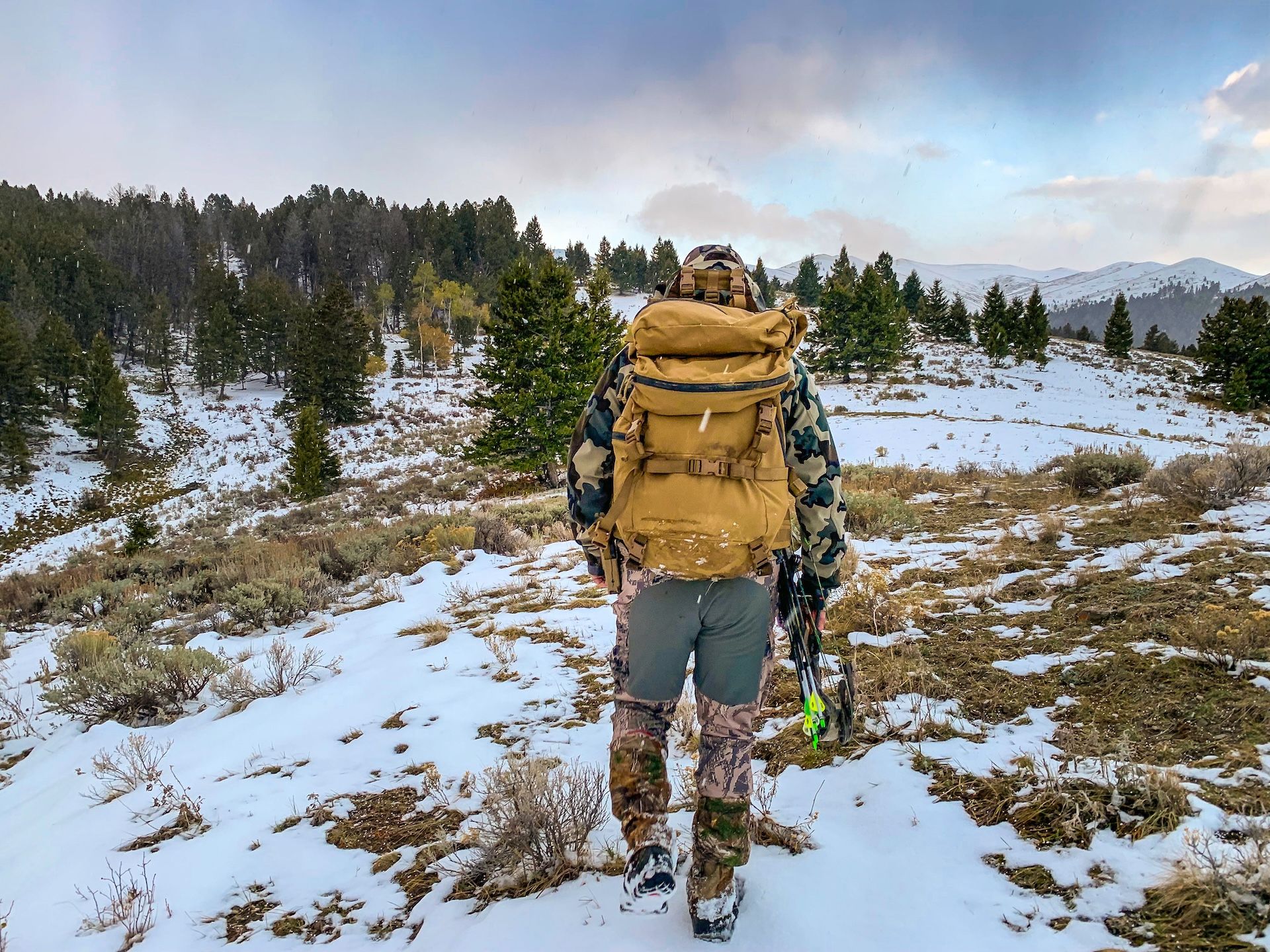 Hunter geared up for an elk hunt walks on snowy ground.