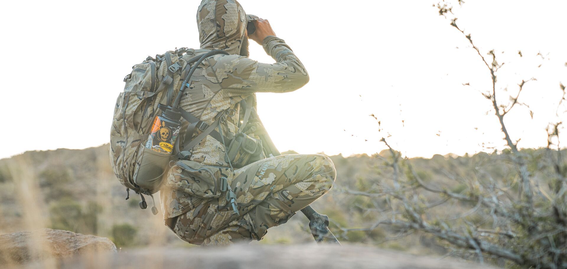 Hunter in camo using binoculars to glass for a hunt.