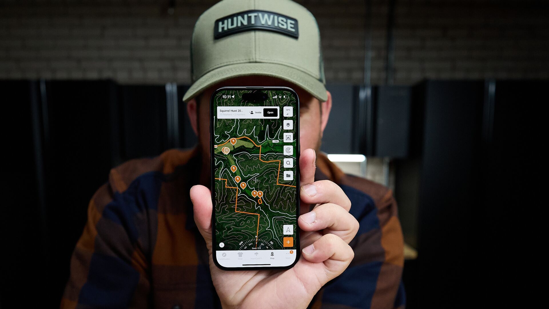 Hunter holds a phone showing HuntWise maps and markers on screen. 