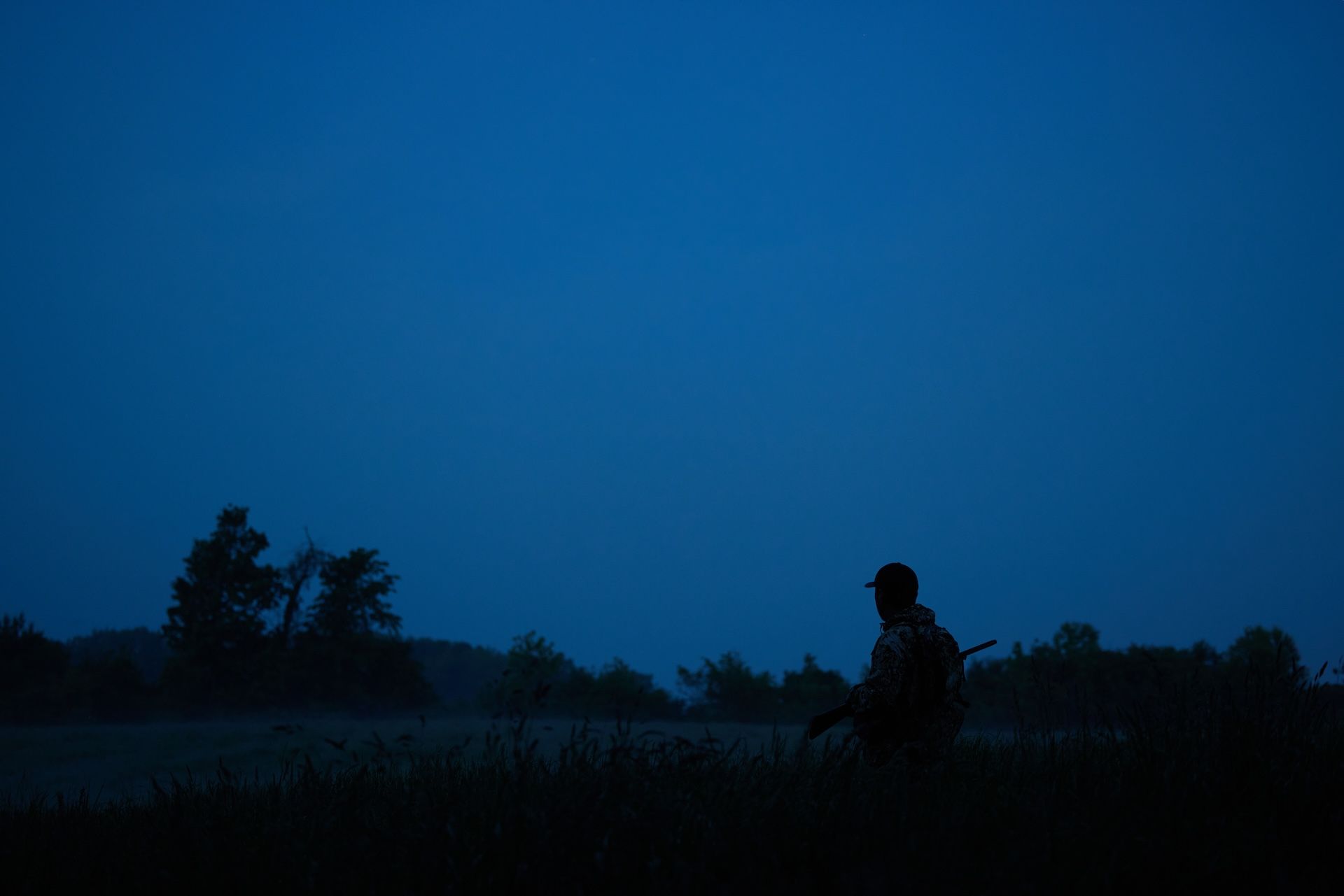 A hunter looks across a field in the dark, night hunting concept. 