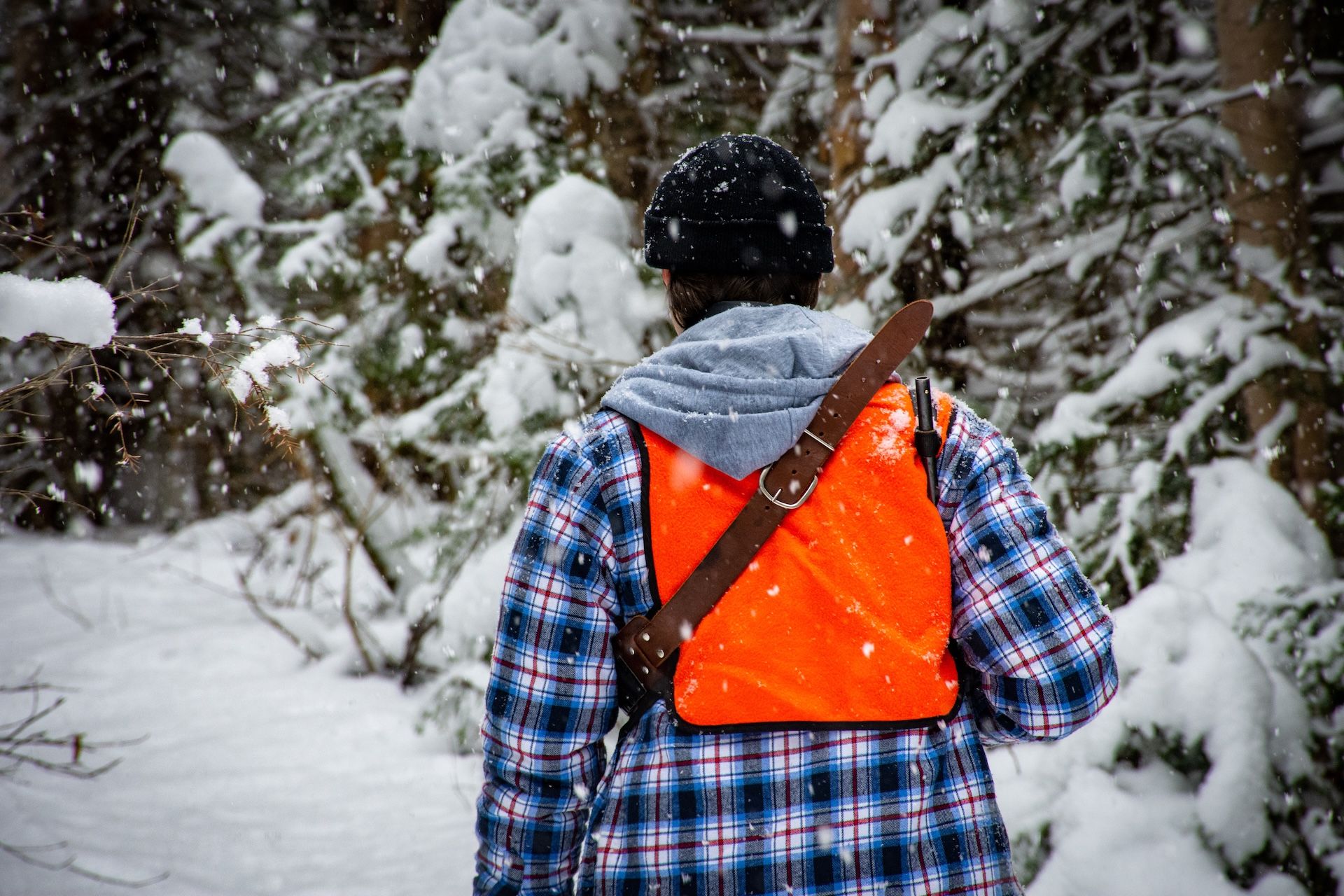Hunter in blaze orange in the snow, small game hunting tips concept. 