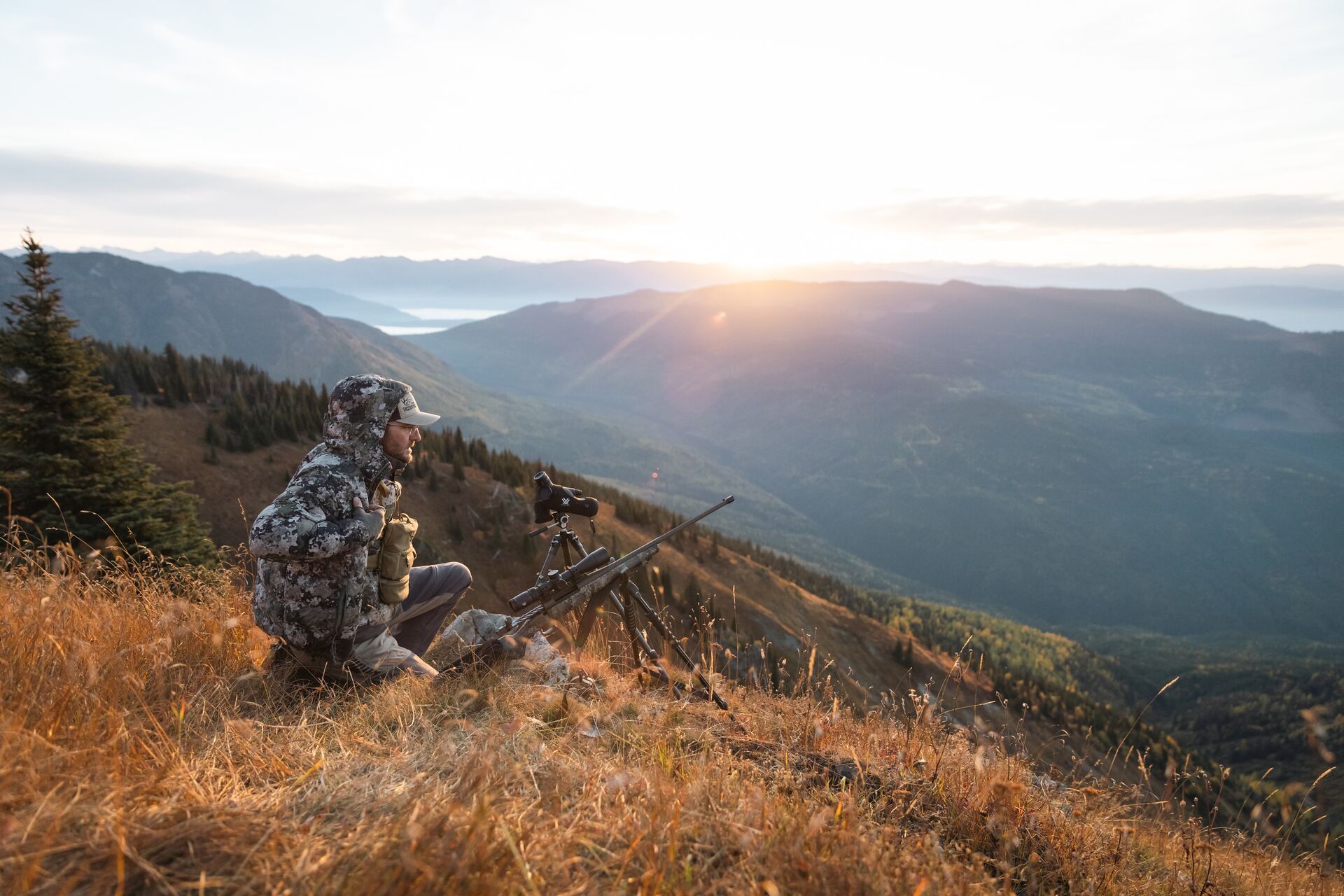 Hunter in camo on a hill with glassing gear, OTC elk tags Wyoming concept. 