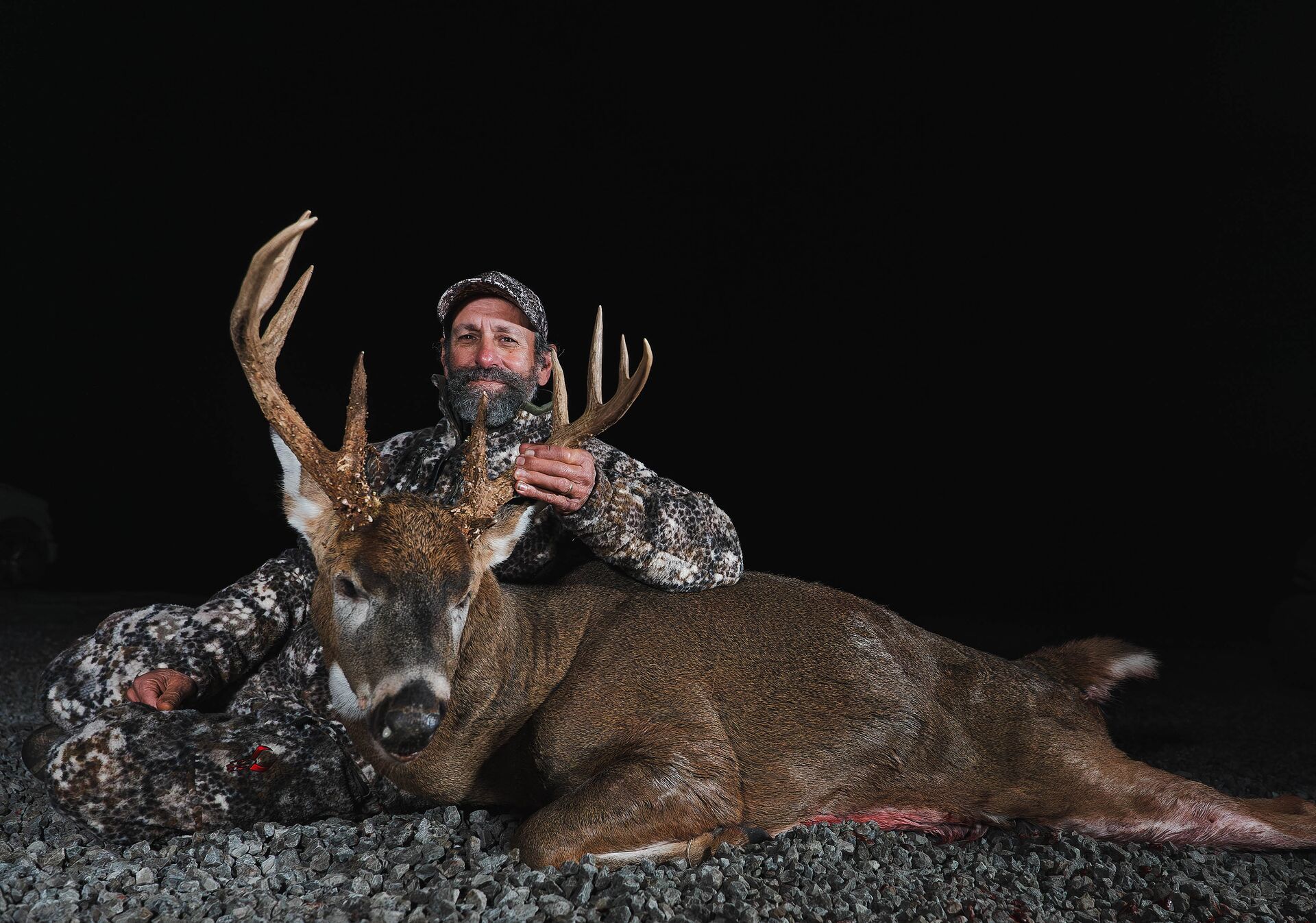 Hunter in camo poses with deer after hunt, deer season Kentucky concept.