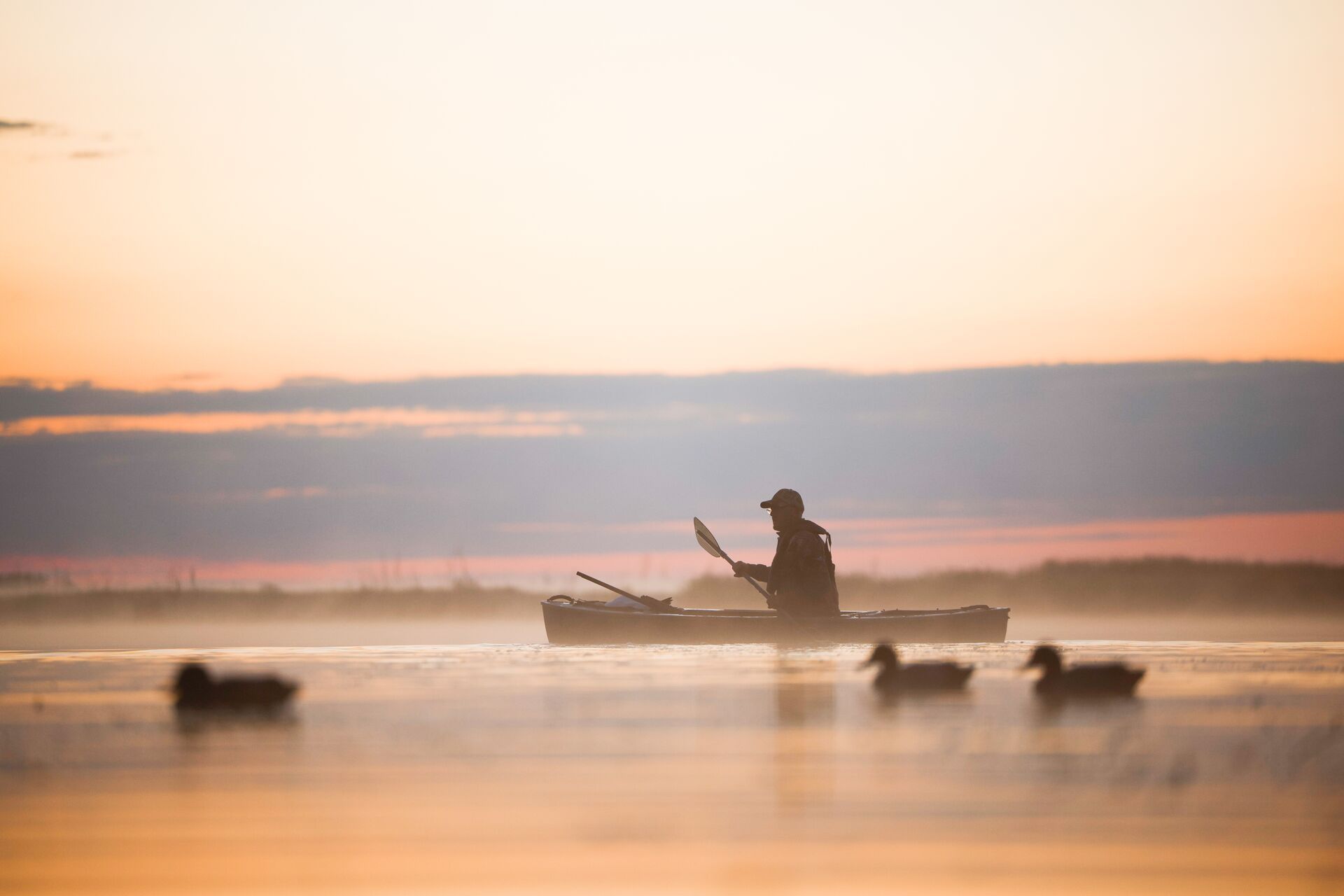 Hunter in canoe on water near duck decoys, waterfowl production area hunting regulations concept. 