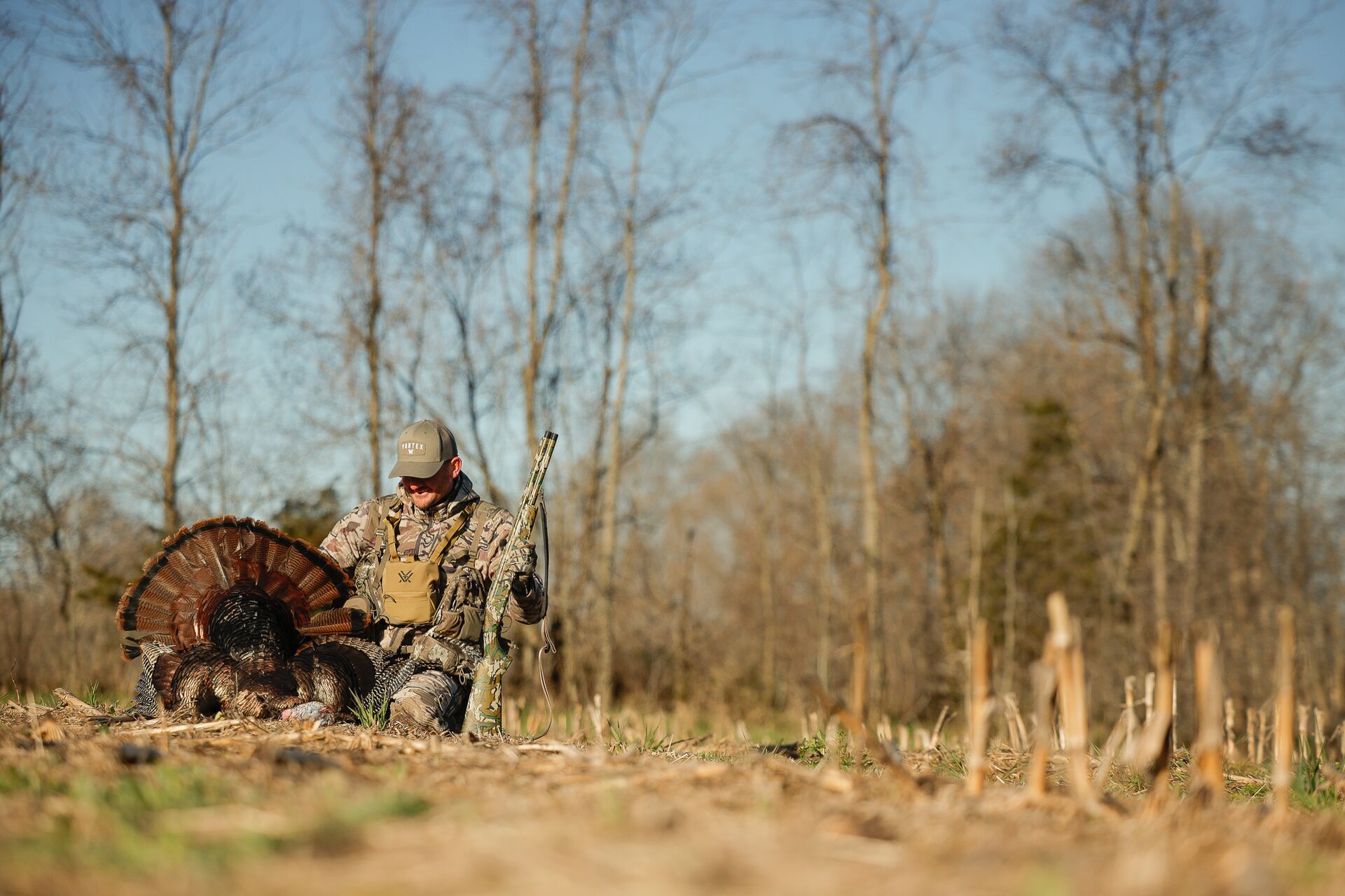 Hunter in a field with a turkey after hunt, hunting vest comparison concept. 