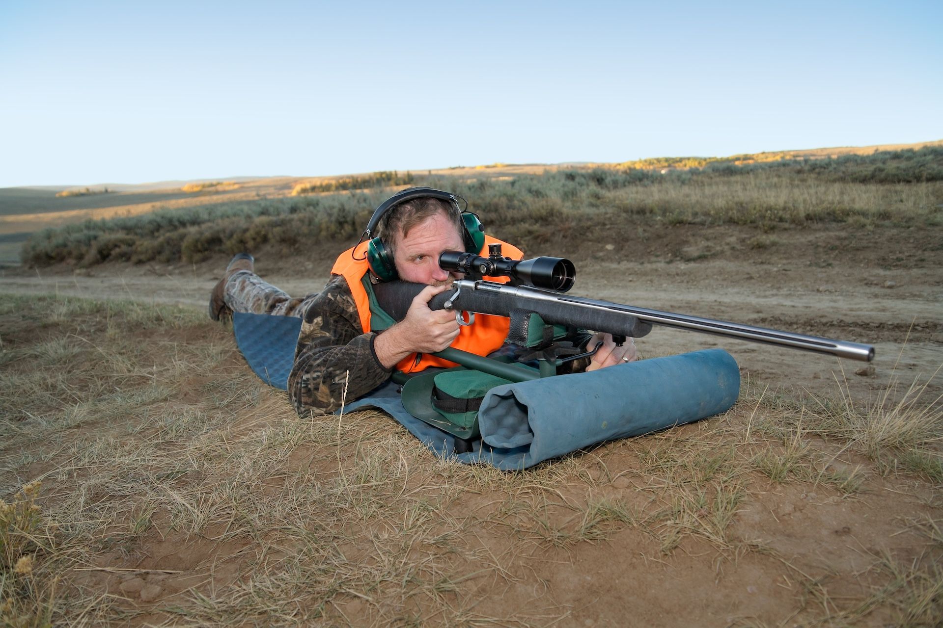 Hunter in prone firing position, proper rifle shooting positions concept. 