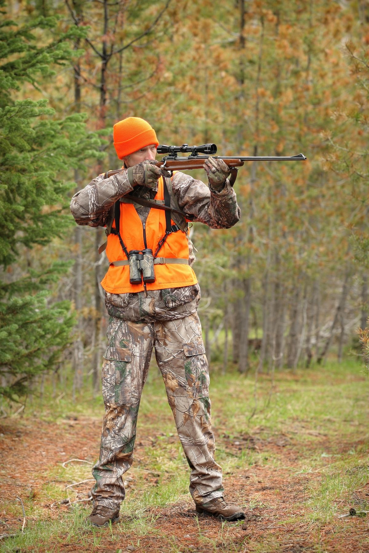 Hunter in blaze orange in standing rifle firing positions.