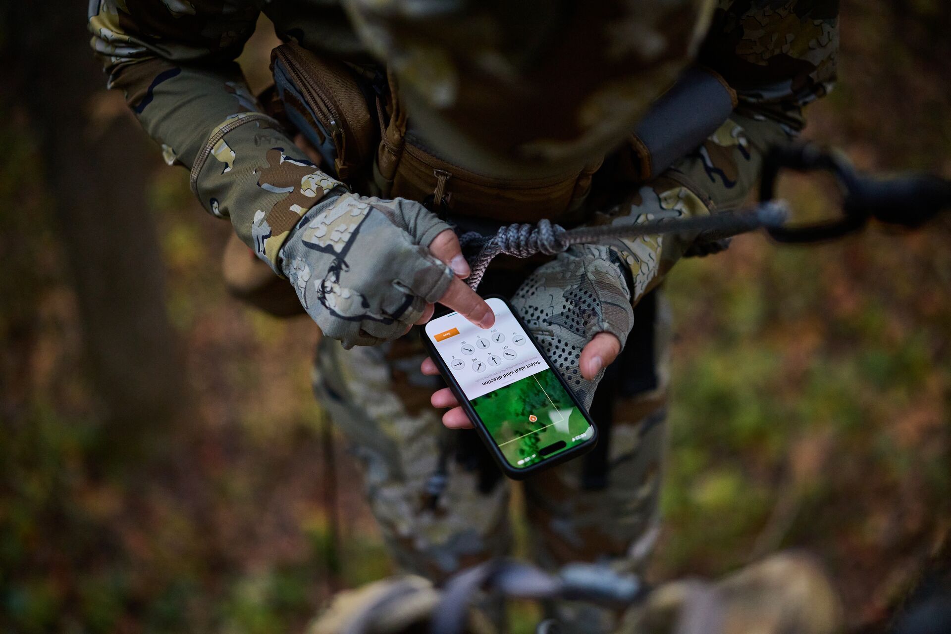 Hunter using HuntWise app on phone while in tree saddle. 