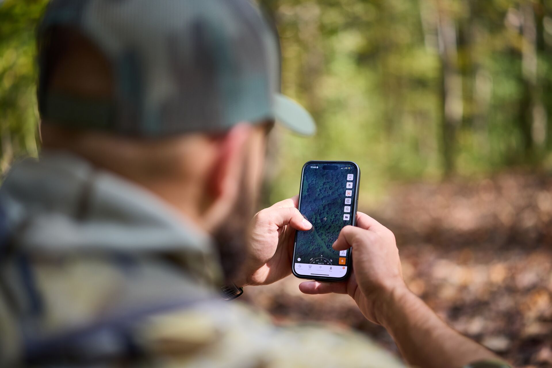 Hunter in the woods uses HuntWise on phone. 