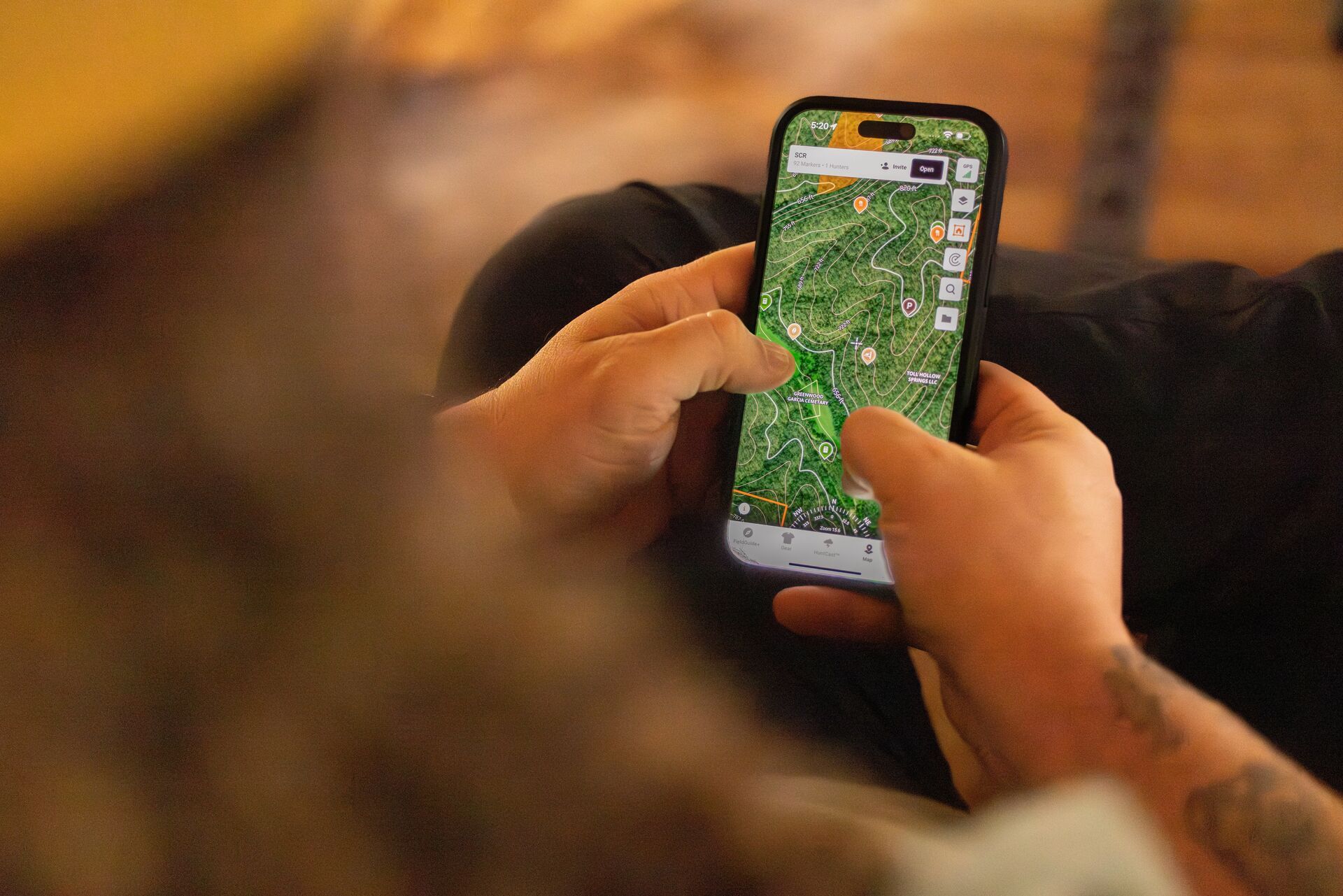 Hunter looks at HuntWise maps on a phone screen, hunting private land concept. 