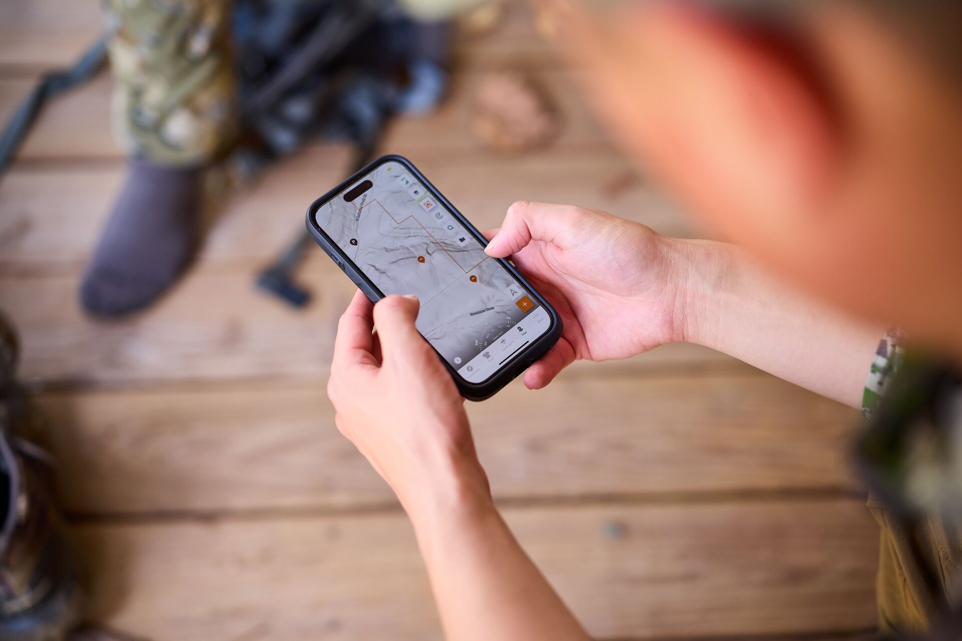 Hunter looks at phone showing HuntWise LiDAR on screen, find best places to hunt rabbits concept. 