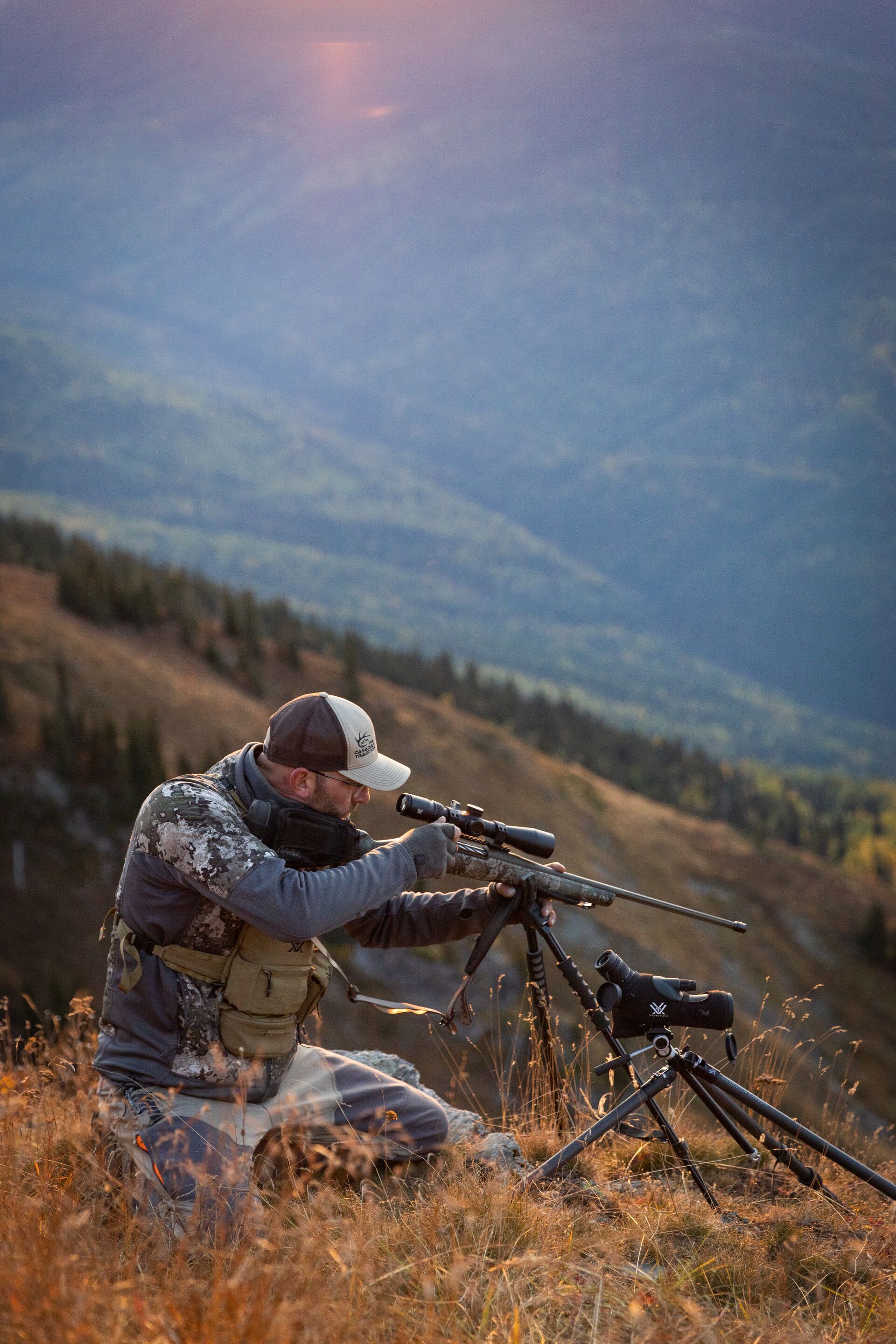 Hunter on a hill aims a rifle, plan guided mule deer hunt concept. 