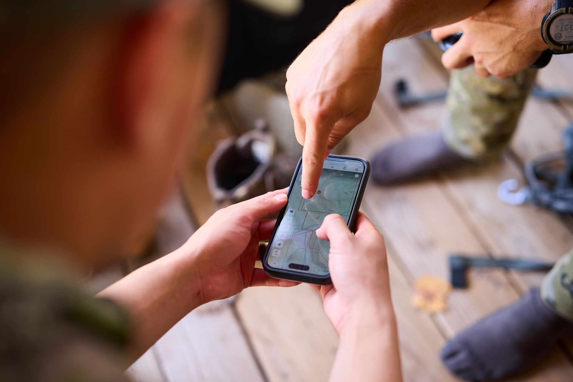 Hunter pointing to phone screen in another hunter's hands, showing HuntWise on screen.
