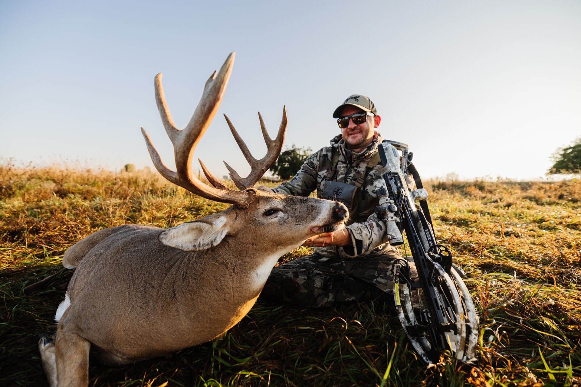 Hunter posing with a big buck deer after a hunt, using HuntCast app concept. 