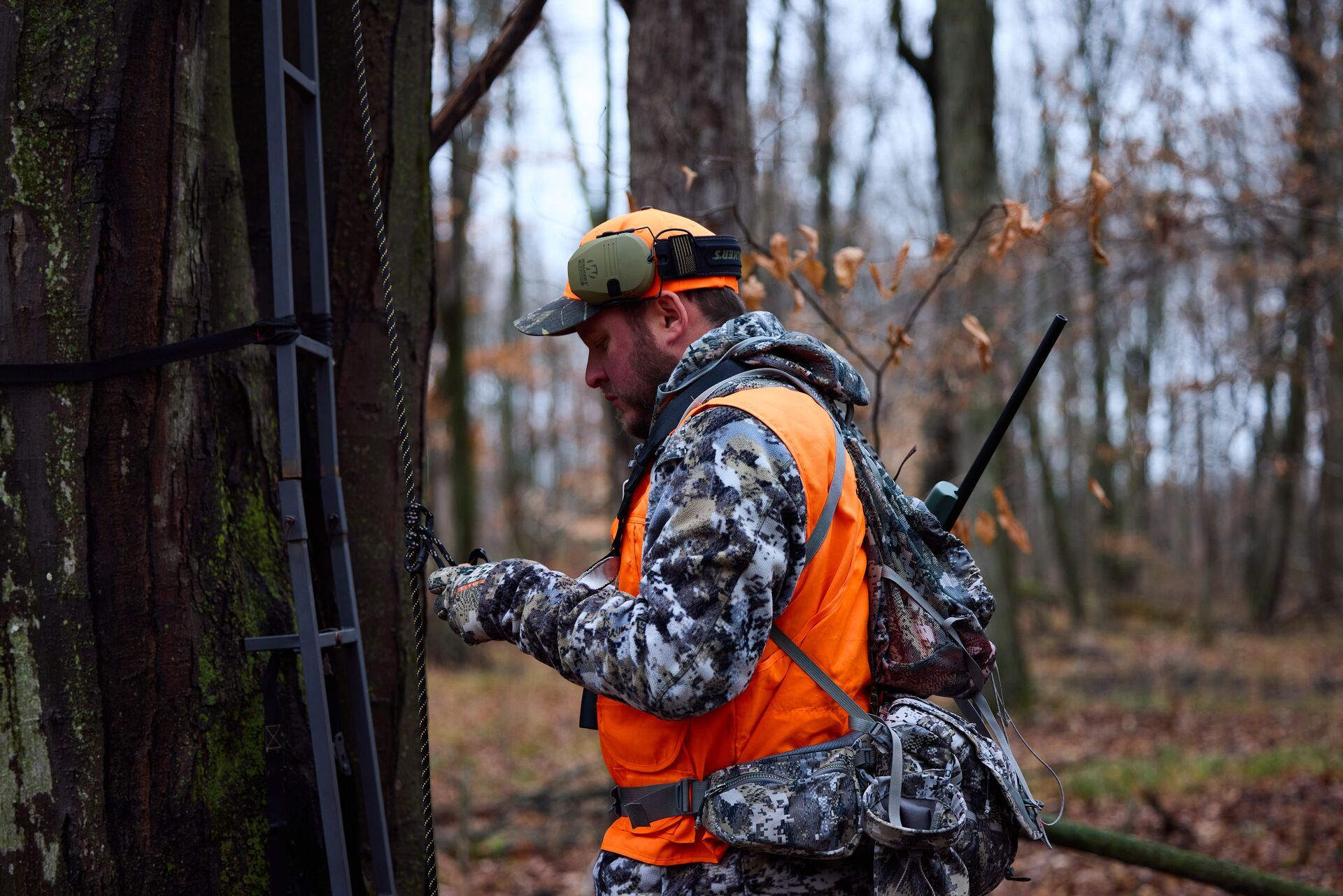 Hunter setting up tree stand ladder. 