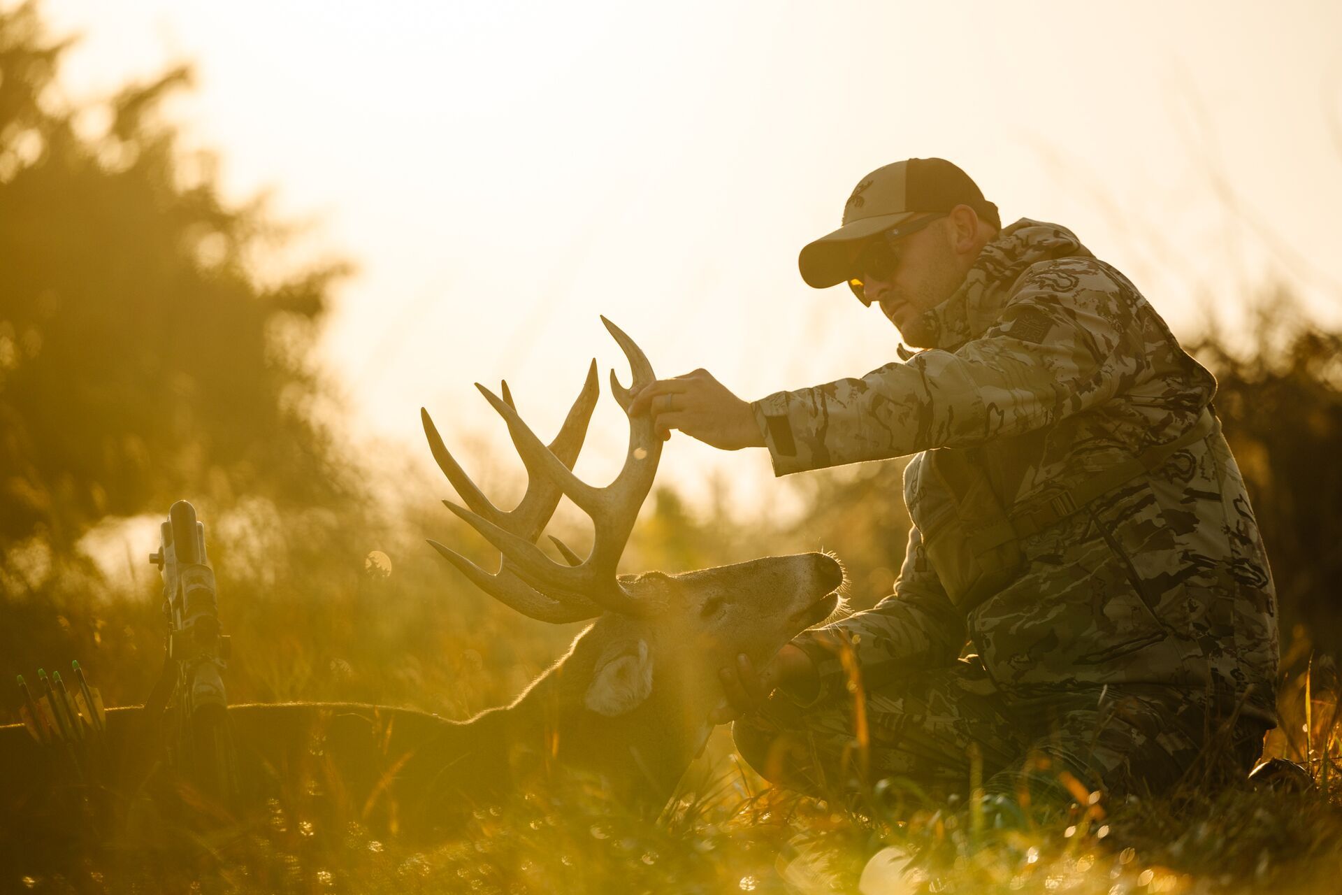 A hunter handles a whitetail buck's head and antlers while on the ground after a hunt. 