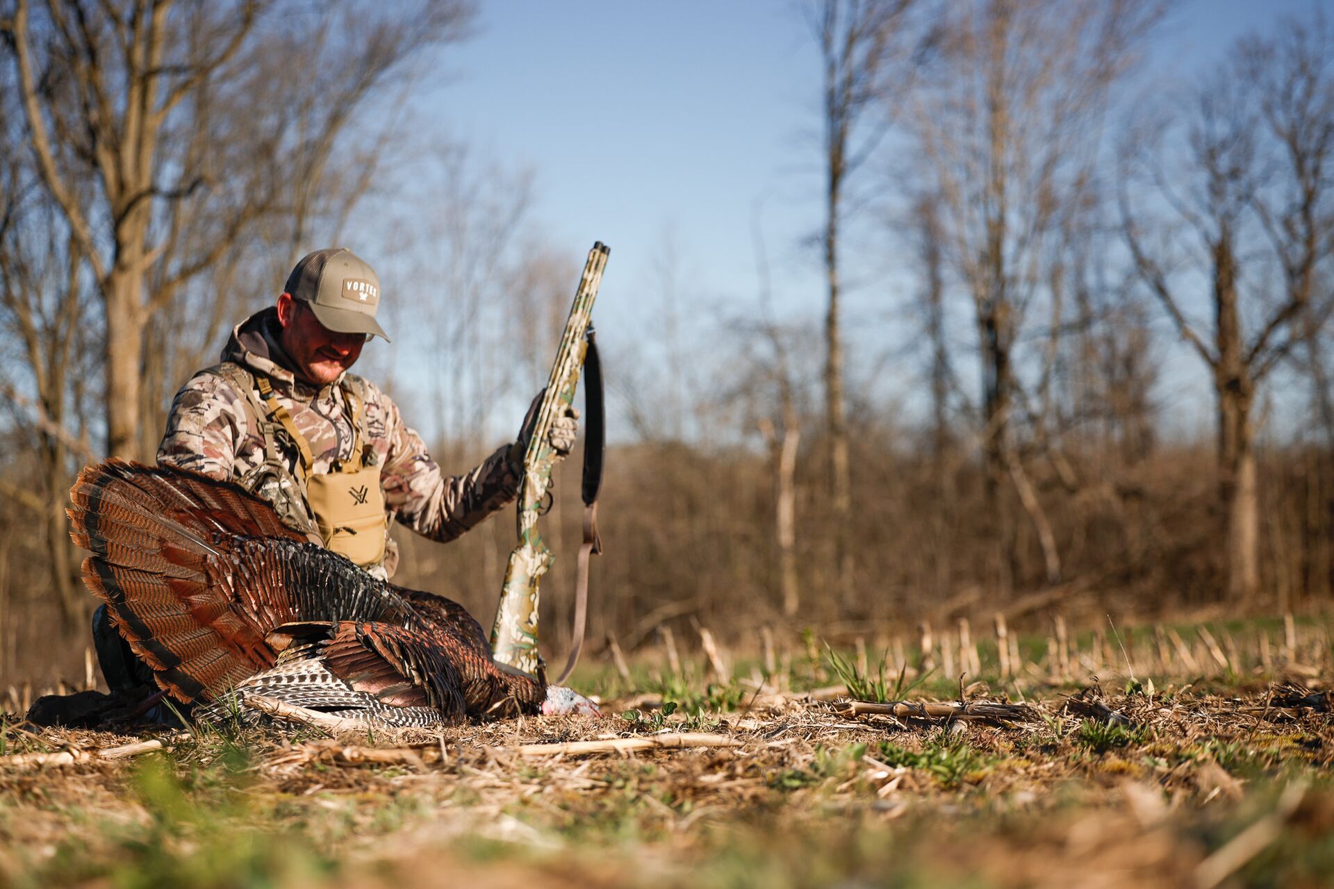 Hunter sits with turkey and rifle after hunt, how to use a turkey box call concept. 