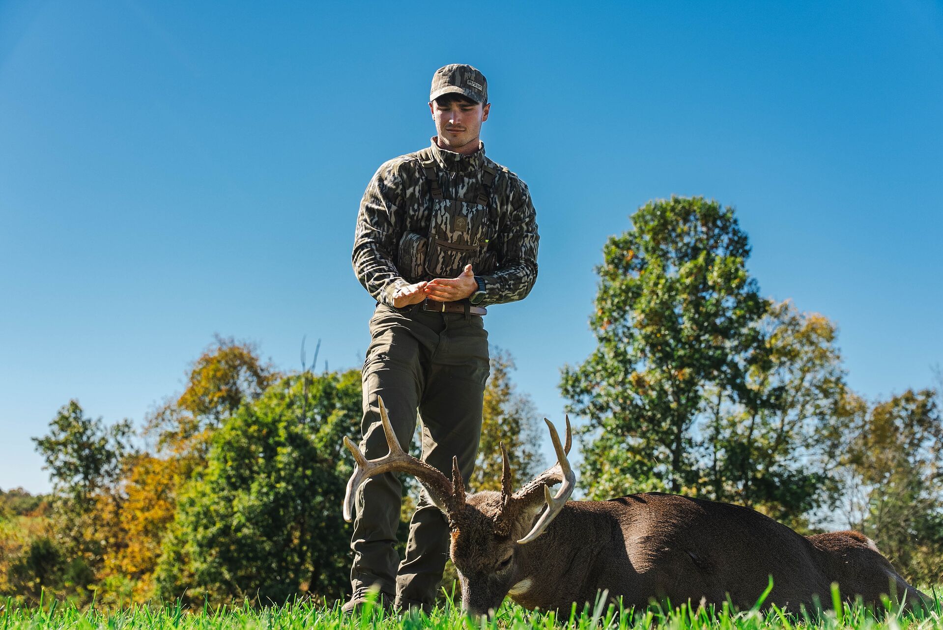 Hunter stands over buck deer on ground after hunt, Minnesota deer season concept.
