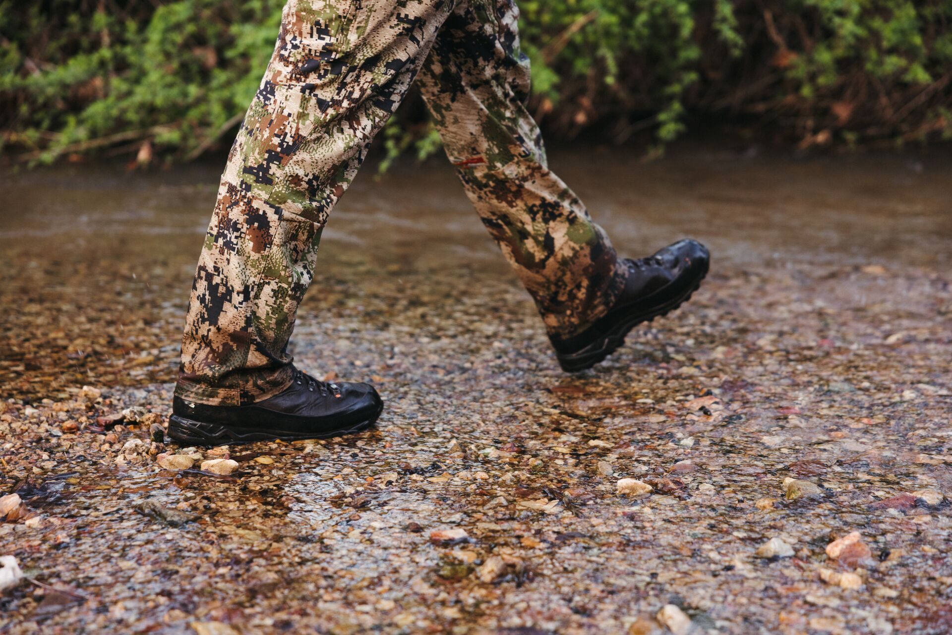 Close-up of a hunter's boots as he walks through water, summer huntingn boots concept. 