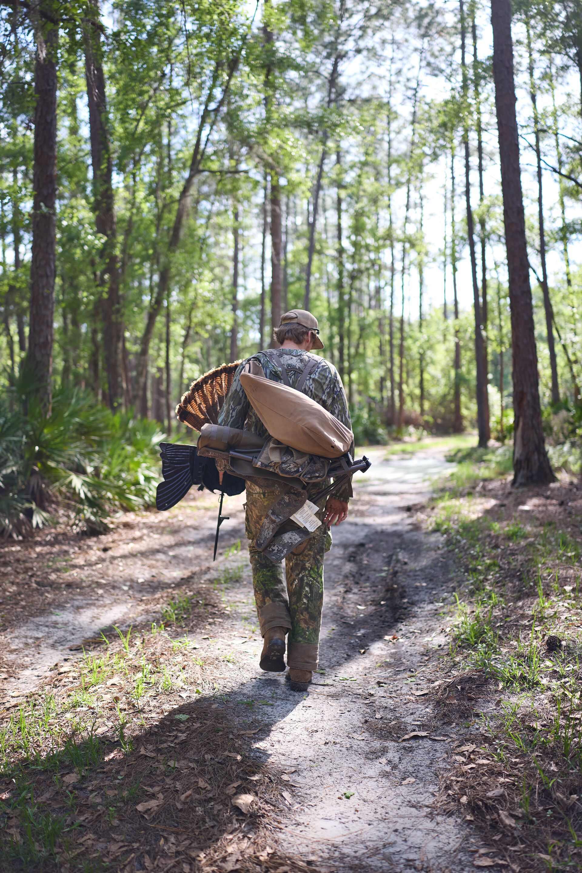 Hunter walks through woods with turkey gear, lightweight turkey vest concept. 